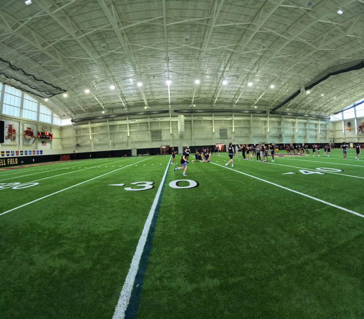 Indoor football field with players practicing.