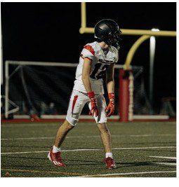 Football player in white and red uniform standing on field.