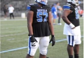 Football player in white and blue uniform standing on the field.