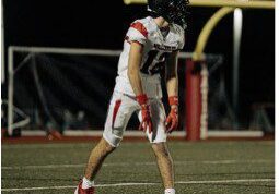 Football player walking on field during game night.