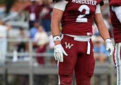 Football player in red Worcester uniform standing on field.